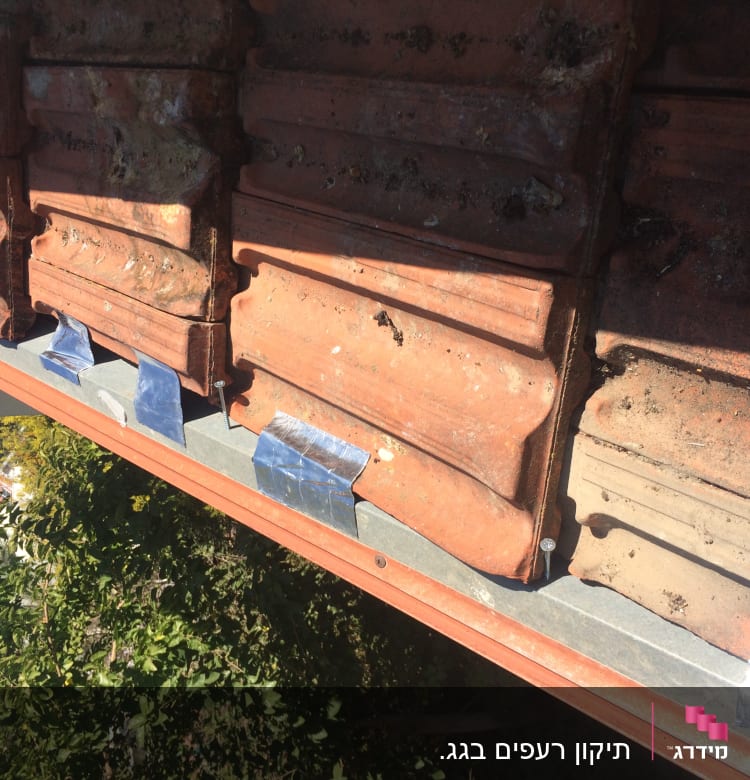 רעפים חומים עם סרטי מתכת על גג